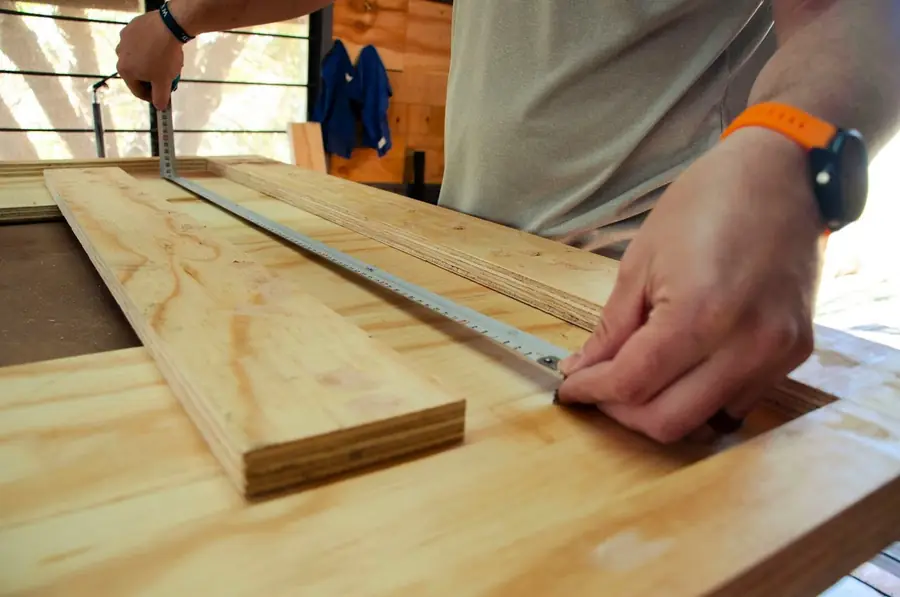 Hände messen ein Holzbrett mit dem Maßband